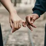 Buying a house together for the first time, A man and a woman holding pinkies