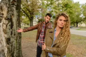 A young couple having an argument in the park, something that happens often when buying a house together with your spouse for the first time