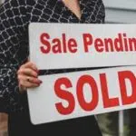 A Realtor replacing a Sale Pending sign with a sold sign