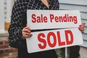 A Realtor replacing a Sale Pending sign with a sold sign