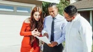 A man and a woman talking to a real estate agent next to a garage door